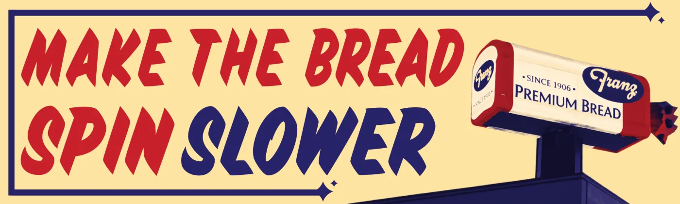 Yellow bumper sticker that reads "Make the bread spin slower" next to the loaf of bread sign on the bakery roof.